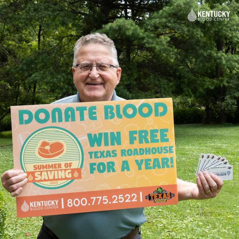 An image of Bernard Batcheldor, the winner of Kentucky Blood Center's free Texas Roadhouse for a year giveaway, holding his prize of Texas Roadhouse gift cards and a KBC sign.